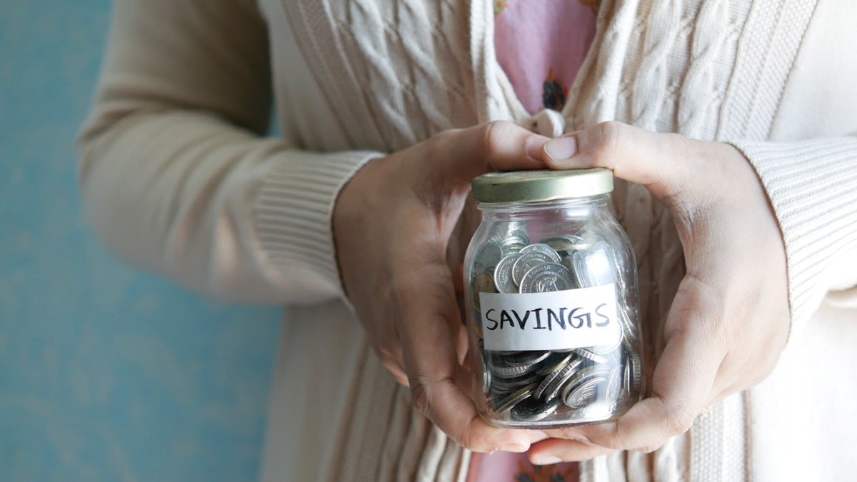 a woman holding a jar with savings written on it