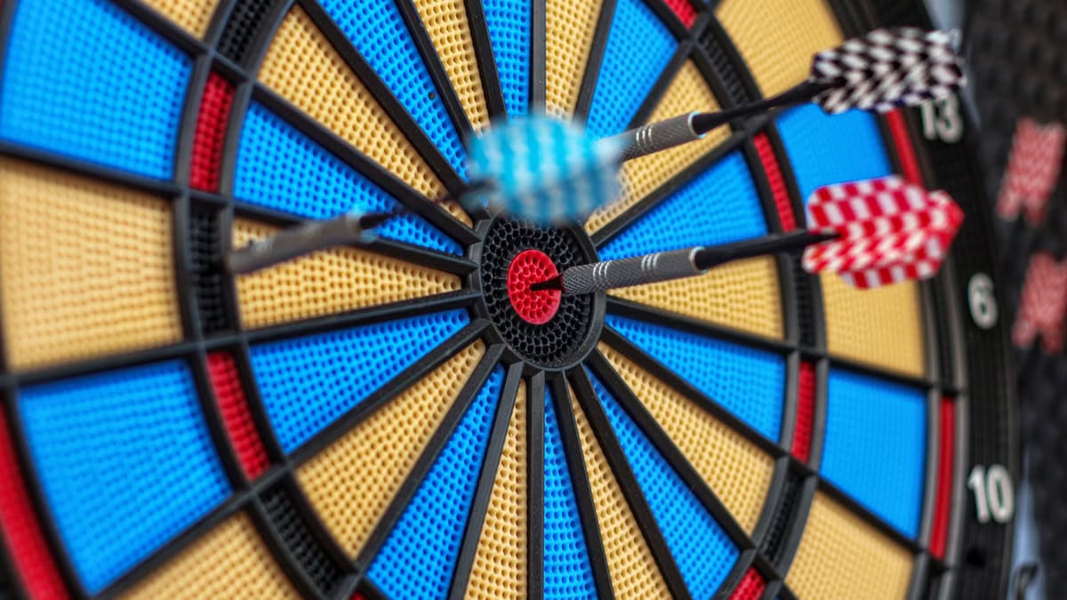Colorful darts hit bullseye on dartboard, capturing precision and focus.